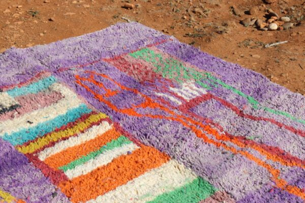 Colorful woven rug on a sandy ground