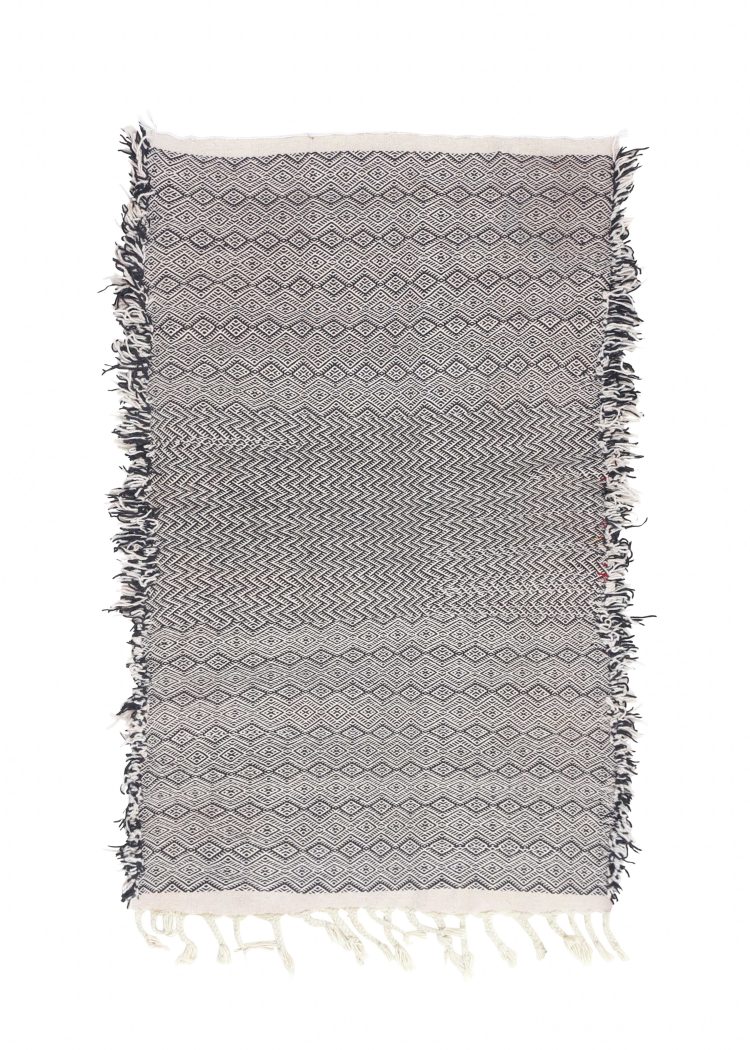 Handwoven Moroccan geometric rug in black and white with intricate patterns by Berber artisans.