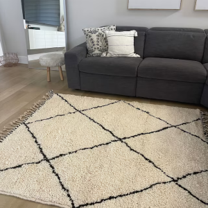 A modern living room featuring a large Beni Ourain rug as the focal point.