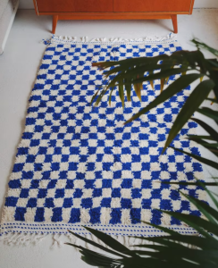 Outdoor blue checkered rug on a patio with furniture.